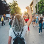 Manifestation d'un mouvement féministe avec une jeune femme levant le poing, entourée de pancartes revendiquant l'égalité des genres dans la société
