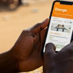 Client utilisant un smartphone pour accéder aux services digitaux d’Orange Burkina Faso via l’application Max it et les codes USSD, illustrant la digitalisation de l’expérience client au Burkina Faso.