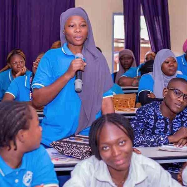 Étudiante intervenant en classe à l’ESC Ouagadougou pendant un cours avec des étudiants en formation de commerce.
